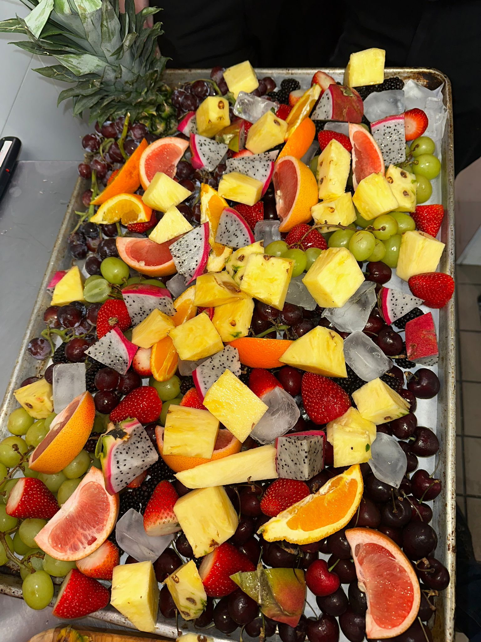 Vibrant fruit platter with dragon fruit, pineapple, berries, and citrus on ice