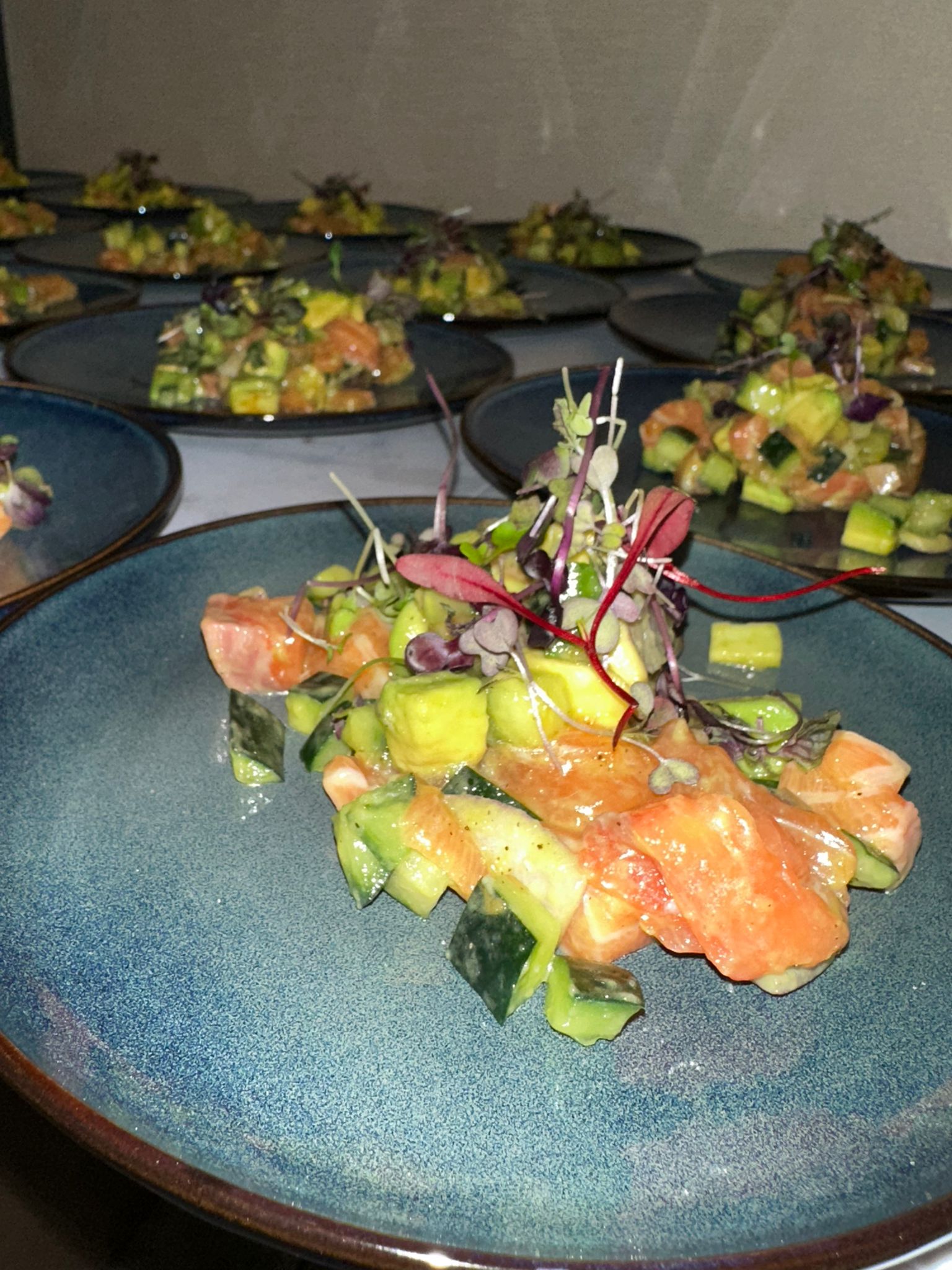 Individual salmon and avocado ceviche appetizers plated on blue ceramic dishes