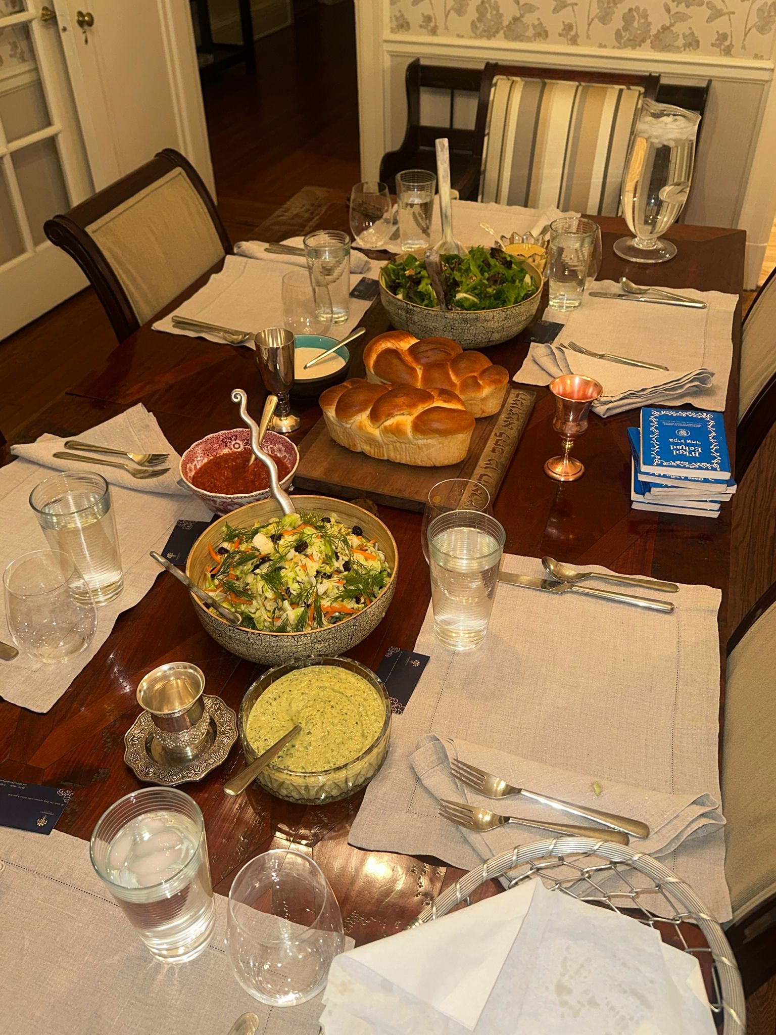 Elegant Shabbat dinner table set with challah, salads, and kiddush cups