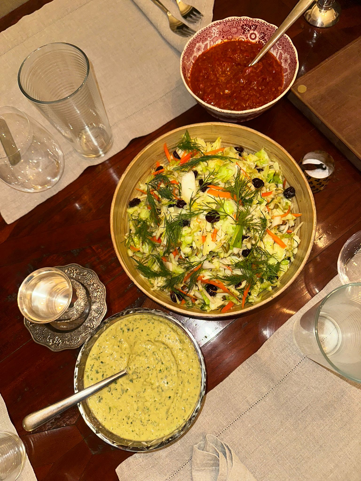 Top-down view of Shabbat table with salads, dips, and kiddush cup